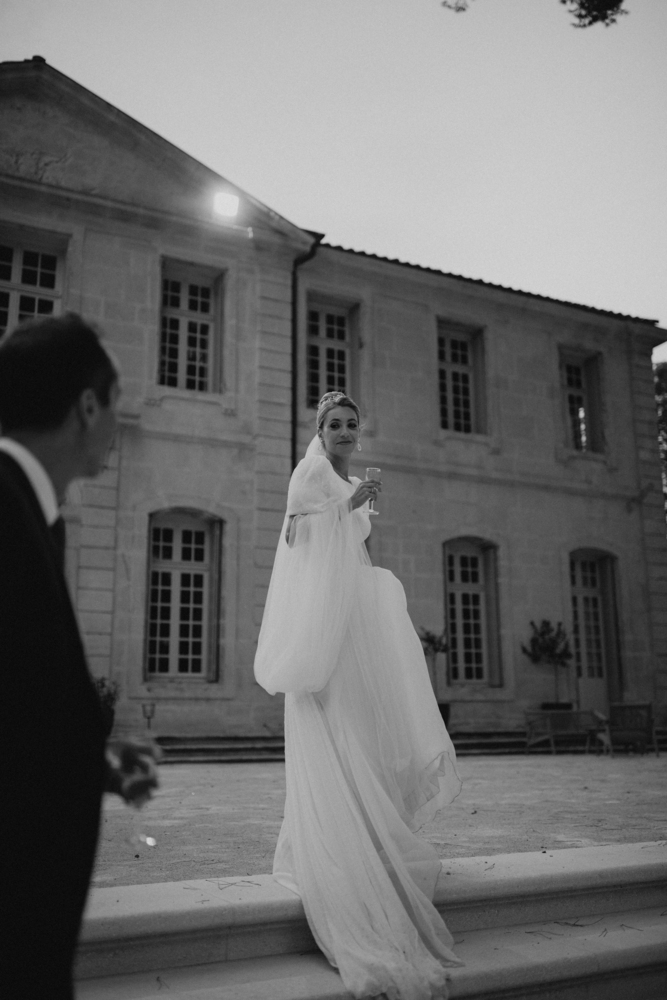 Mariée joyeuse avec une coupe de champagne – Instant de grâce et de célébration au cœur de l’Hérault.