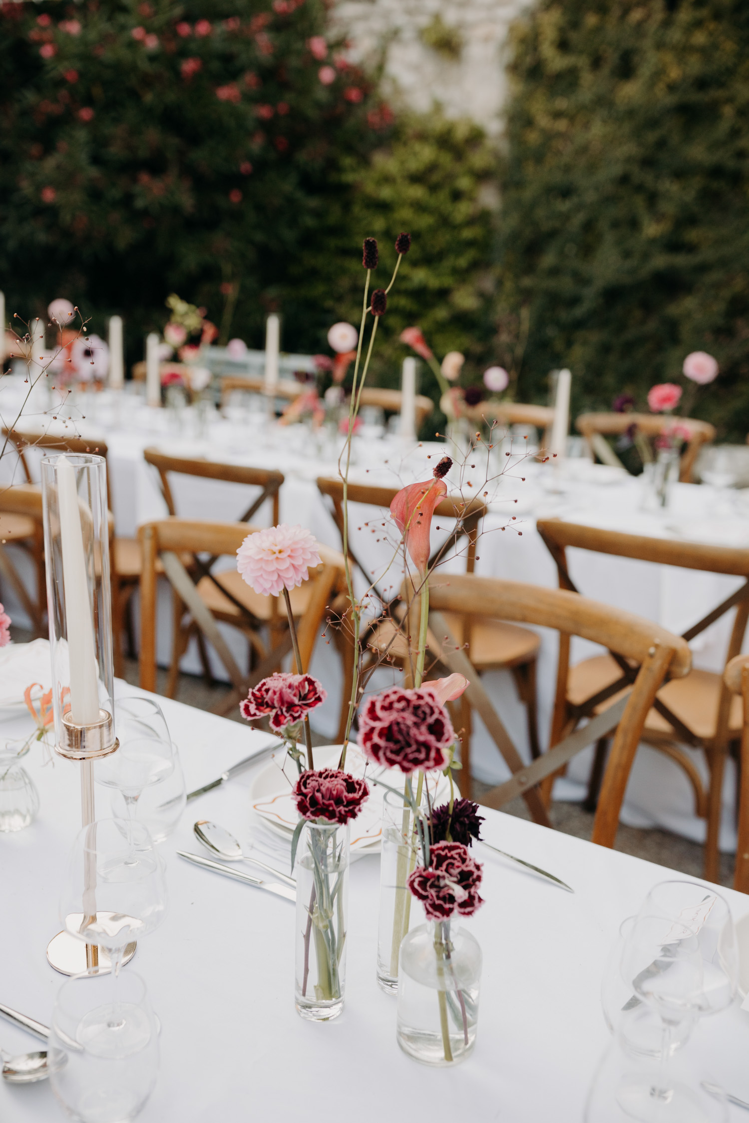 Decoration de mariage élégante avec des tables organisées en banquet et des fleurs roses et rouges, et des vases allonges