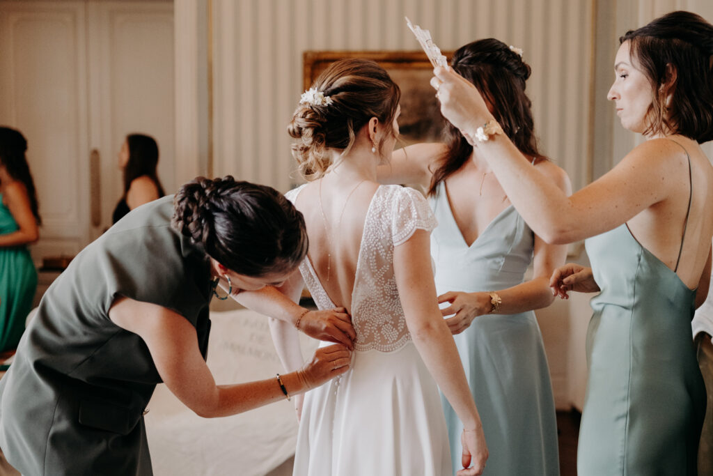 Mariage luxueux en Occitanie au Château de Malmont, sur la photo on voit les demoiselles d'honneur entrain d'habiller la mariée
