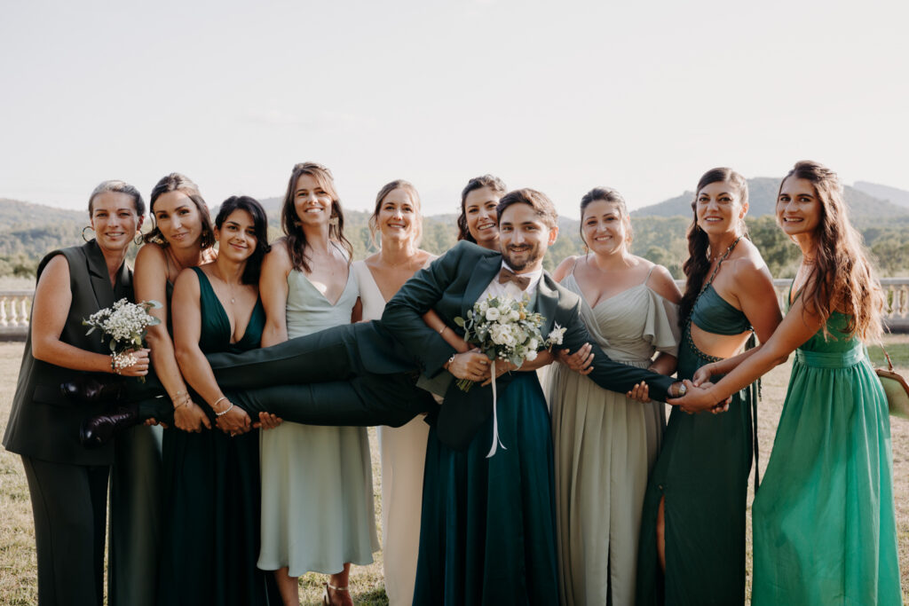 les demoiselles d'honneur portent le marié pendant les photos de groupe