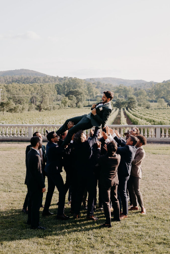 le marié est porté par ses temoins pendant les photos de groupe