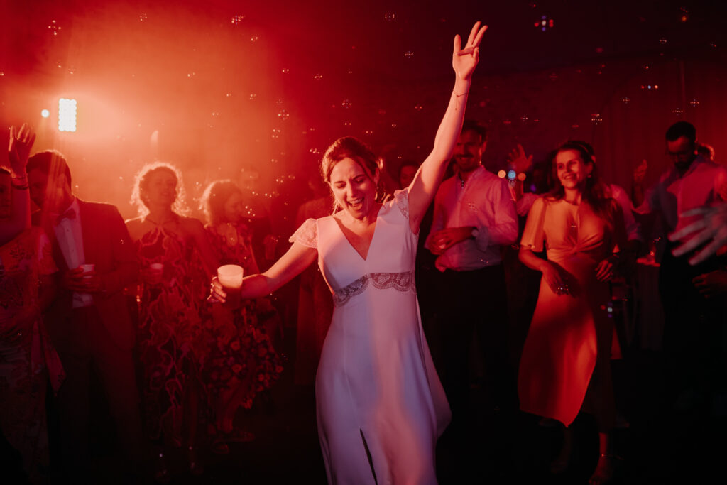 La mariée est entrain de danser sur la piste de danse du Château de Malmont un verre à la main photographiée par Emélie Carlier - photographe de mariage à Montpellier